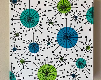 May include: A white canvas painting featuring a repeating pattern of black, green, and blue stylised flowers. The flowers have a circular centre and radiating lines.