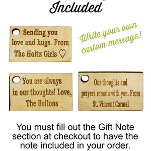 May include: Three wooden gift tags with different messages. The first tag says "Sending you love and hugs. From The Holtz Girls". The second tag says "You are always in our thoughts! Love, The Boltons". The third tag says "Our thoughts and prayers remain with you. From St. Vincent Carmel".