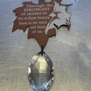 May include: A brown leaf-shaped metal ornament with a bird design and the text "Through the STRONGEST of storms or the softest breeze listen to the wind and think of me". A clear crystal prism hangs from the ornament.