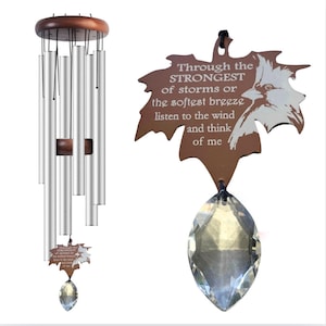 May include: A silver wind chime with a wooden top and a crystal prism hanging from the bottom. The chime is attached to a brown wooden leaf with the inscription "Through the STRONGEST of storms or the softest breeze listen to the wind and think of me".