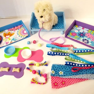May include: A set of dog accessories for a small dog, including two blue and purple dog beds, two pink and green bone-shaped food and water bowls, a white plush dog, a blue and white lead, and a variety of colourful dog toys.