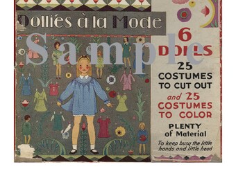 Op de afbeelding: Een vintage doos met papieren poppen met de tekst "Dollies à la Mode" en "6 Poppen". De doos heeft een kleurrijke illustratie van een meisje in een blauwe jurk en andere poppen met verschillende outfits. De tekst op de doos vermeldt ook "25 Kostuums om uit te knippen en 25 Kostuums om in te kleuren".