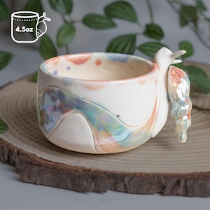 May include: A white ceramic mug with a black handle and the text "But First, Coffee" in a handwritten style. The mug is on a white surface. The mug is 4 inches tall.