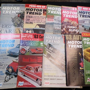 May include: A collection of vintage Motor Trend magazines, featuring various car models and racing events. The covers display bold titles, dates, and colorful illustrations of classic cars, with text like "Road Tests" and "Turbo Super".
