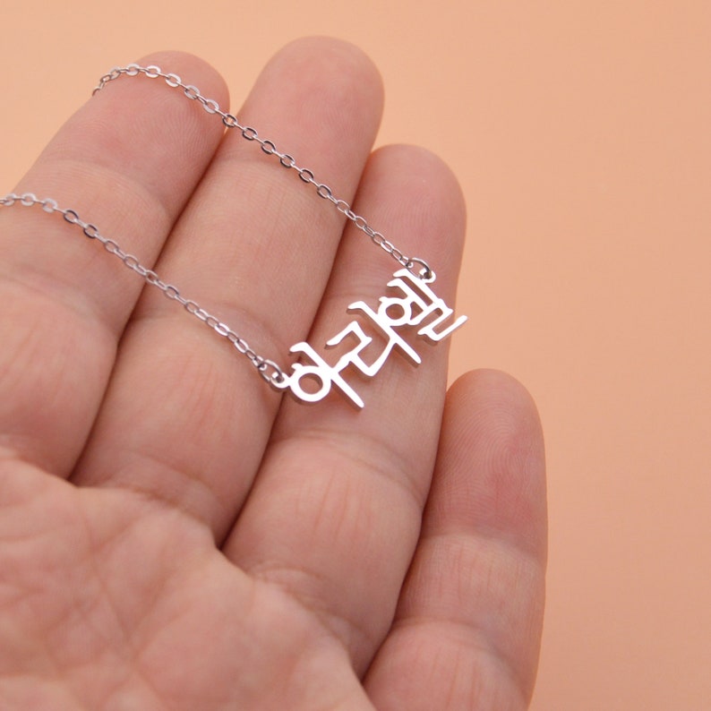 Pu&ograve; includere: Collana d'argento con un ciondolo con una parola coreana. La parola &egrave; "notevole" in coreano.