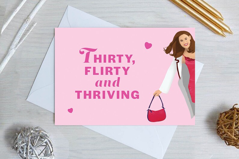 Pu&ograve; includere: Biglietto di auguri rosa con una donna in giacca bianca e vestito rosa che tiene una borsa rossa. Il biglietto dice "Thirty, flirty and thriving" in lettere rosa.