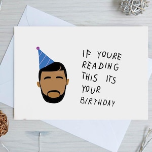 May include: A white birthday card with the text "IF YOU'RE READING THIS ITS YOUR BIRTHDAY". The card features a cartoon illustration of a person wearing a blue party hat. The card is placed on a white envelope.