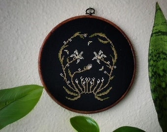 May include: A black embroidery hoop with a gold floral design on a black background. The design features stylized flowers and leaves.