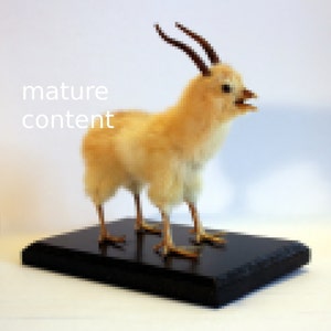 Può includere: Un pollo imbalsamato con le corna in piedi su una base di legno nero. Il pollo è di colore marrone chiaro e ha un collo lungo e un becco.