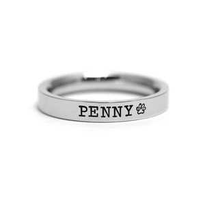 May include: A silver ring with the name "PENNY" and a paw print engraved on it.