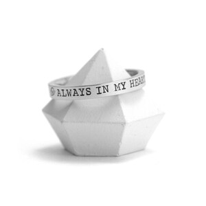 Op de afbeelding: Een zilveren ring met de inscriptie "ALWAYS IN MY HEART".