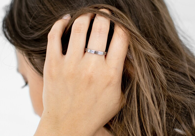 Op de afbeelding: Een zilveren ring met de inscriptie "This Too Shall Pass" gegraveerd op de band.