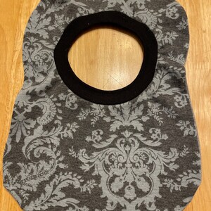 May include: A grey and white patterned bib with a black trim around the neck opening.