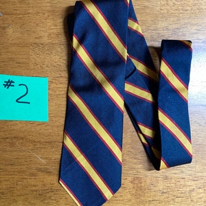 Puede incluir: Una corbata azul oscuro con rayas gruesas amarillas y rojas.