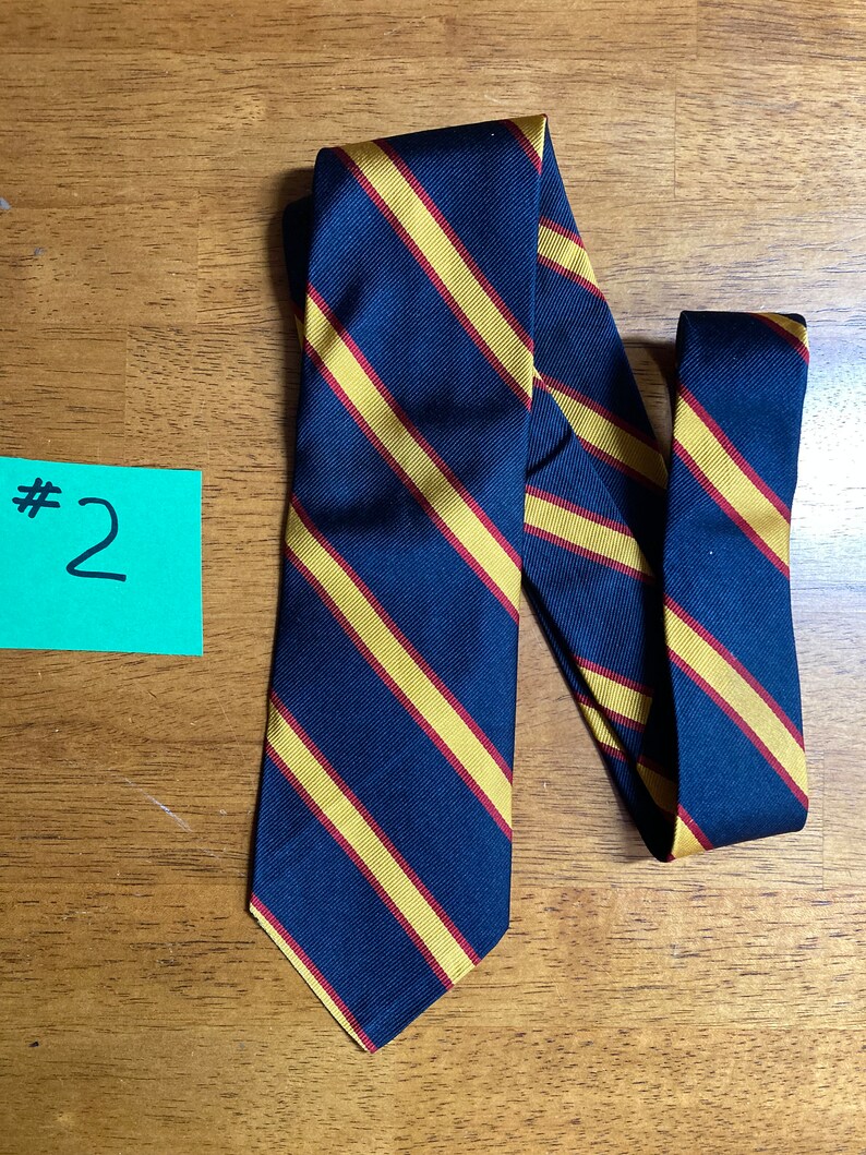 Puede incluir: Una corbata azul oscuro con rayas gruesas amarillas y rojas.