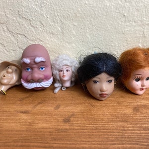 Doll heads and limbs for construction and repair, including a old woman with a yellow hat, a bride, and extra limbs
