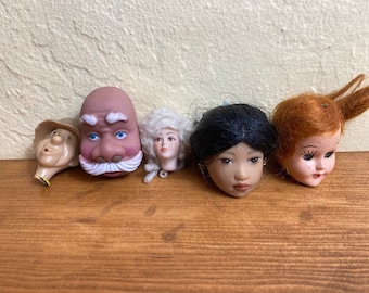 Doll heads and limbs for construction and repair, including a old woman with a yellow hat, a bride, and extra limbs