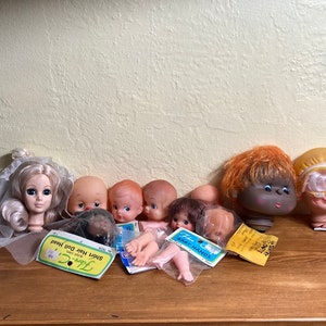 Doll heads and limbs for construction and repair, including a old woman with a yellow hat, a bride, and extra limbs