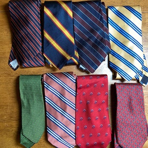 May include: A collection of ten striped and patterned neckties in various colors, including red, blue, green, yellow, and brown.