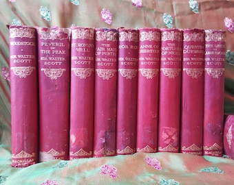 Op de afbeelding: Een verzameling van tien vintage hardback boeken van Sir Walter Scott, met rode omslagen en gouden letters. De titels omvatten "Woodstock", "Peveril of the Peak", "St. Ronan's Well", "The Fair Maid of Perth", "Rob Roy", "Anne of Geierstein", "The Fortunes of Nigel", "Quentin Durward", en "The Bride of Lammermoor".
