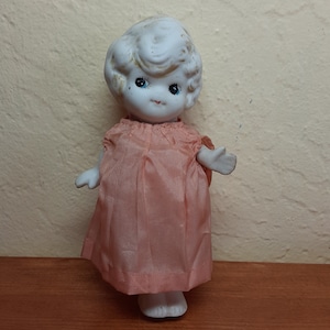 1920s small Japanese bisque Kewpie doll with pink and red bathing suit painted directly onto the doll along witha hand-made pale pink dress