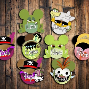 May include: Set of 8 green, brown, and yellow Disney-themed character head ornaments with names "Levi", "Janita", "Dad", "Emma", "Nana", "Mom", "Papa", and "Cohen".