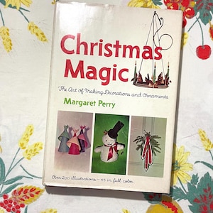 May include: A vintage book titled "Christmas Magic: The Art of Making Decorations and Ornaments" by Margaret Perry. The cover features a festive illustration of a snowman, a wreath, and a chandelier with candles. The book includes over 200 illustrations, with 45 in full color.