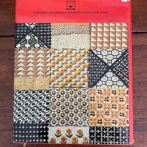 May include: A vintage book cover with a red top and a patchwork design of various needlepoint patterns in black, white, yellow, and brown. The text "PUBLISHED BY CHARLES SCRIBNER'S SONS/NEW YORK" is printed on the red top.