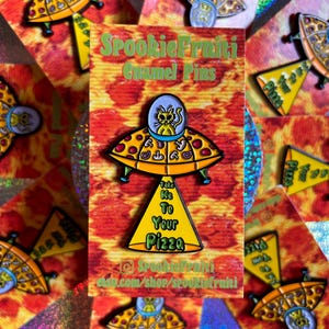 May include: Enamel pins featuring a cat alien in a pizza-shaped UFO. The pins have yellow, orange, and blue accents, with the text "Take Me To Your Pizza." The pins are displayed on cards with a pizza and holographic background.