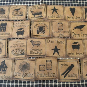May include: A collection of rustic, brown paper tags with black illustrations and text. The tags feature various images like a crow, sheep, star, and jar, with phrases such as "Prim Bees" and "Primitive Home."