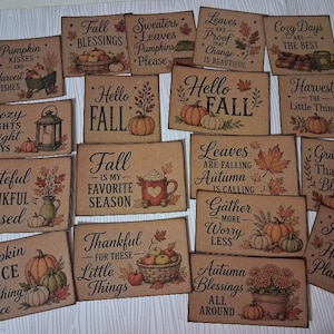 May include: A collection of rectangular wooden signs featuring autumn-themed illustrations and text including Pumpkin Kisses, Hello Fall, Cozy Days, Grateful Thankful Blessed, and Autumn is My Happy Place, decorated with pumpkins, leaves, and mugs.