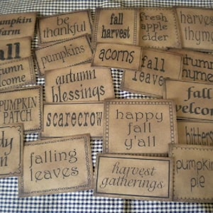 May include: A collection of brown paper signs with fall-themed text, such as "pumpkin farm", "fall harvest", "autumn blessings", and "happy fall y'all".