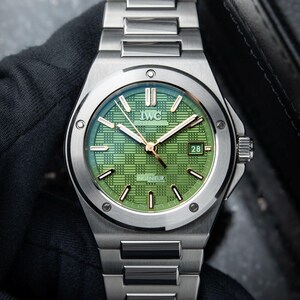 Peut inclure: Une montre-bracelet en acier inoxydable argenté dotée d'un cadran vert texturé avec un motif à grille. Le cadran affiche le logo IWC, le mot INGENIEUR et un guichet de date indiquant le chiffre 28. Elle possède des aiguilles et index argentés.