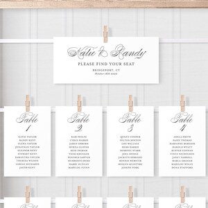 May include: A wedding seating chart with eight tables, each with a table number and a list of names. The chart is displayed on a white background with a wooden frame.