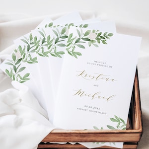 May include: White wedding program with green foliage and white flowers. The text reads "Welcome to the wedding of Kristina and Michael 08.16.2045 Newport, Rhode Island".