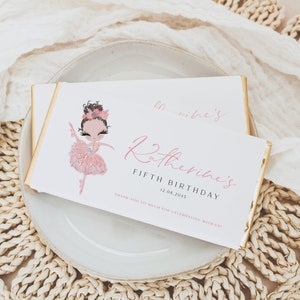Può includere: Un involucro di barretta di cioccolato bianco con un'illustrazione di ballerina rosa e il testo "Katherine's Fifth Birthday 12.08.2015 Thank you so much for celebrating with us!"