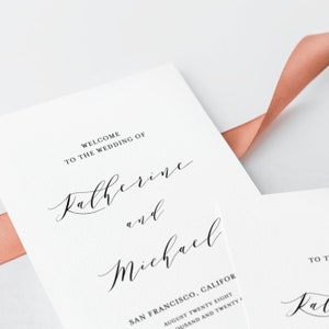 May include: Wedding invitation with a white background and black text. The text reads "Welcome to the wedding of Katherine and Michael" followed by the wedding location and date.