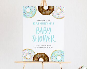 Puede incluir: Bienvenido al Baby Shower de Katheryn con temática de donas. El cartel presenta tres donas de acuarela con chispas en azul, marrón y blanco.
