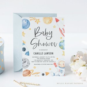 May include: A baby shower invitation with a watercolor illustration of planets, stars, and a rocket ship. The text reads "Baby Shower" in honor of Camille Lawson. The event is scheduled for Saturday, August 15 at 2:30 PM at The Hudson Home, 178 Maine St, Toronto, ON. RSVP by August 5 to 888 987 6543. Registered at Pottery Barn Kids.