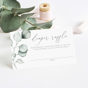 May include: A white card with green eucalyptus leaves printed on it. The card says "diaper raffle" and "Please bring a pack of diapers in any size, to be entered to win a special prize!" with a line for a name.