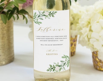 May include: A white wine bottle with a personalized label. The label features a floral design with green leaves and white flowers. The text on the label reads "Katherine I need something old, something new something borrowed, something blue and most importantly... you! Will you be my bridesmaid? with love Kristina".
