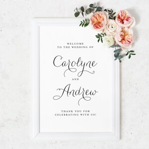 Pode incluir: Um sinal de casamento emoldurado em branco com texto em caligrafia preta que diz "Bem-vindos ao casamento de Carolyne e Andrew. Obrigado por celebrar conosco!"