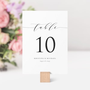 May include: White table number card with black calligraphy that says "table 10" and the names "Kristina & Michael" with the date "August 18, 2045".