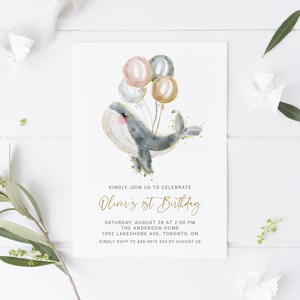 May include: A blue whale with gold glitter holding pink, gray, and gold balloons. The text "Oliver's 1st Birthday" is written in gold script. The invitation includes the date, time, location, and RSVP information.