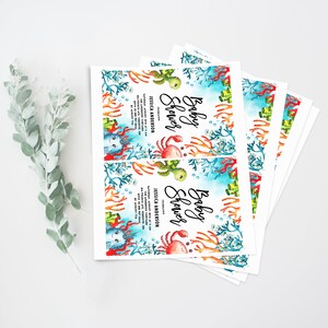 May include: A stack of baby shower invitations with a blue and green watercolor background featuring a crab, a turtle, and coral. The text on the invitation reads "Baby Shower" and includes the date, time, and location of the event.