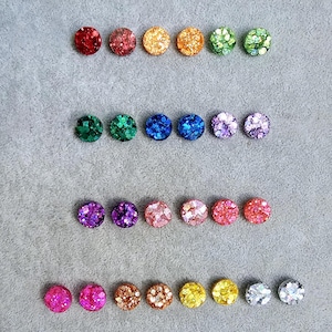 May include: Assortment of 20 pairs of small round glitter stud earrings in various colors, including red, orange, yellow, green, blue, purple, pink, and silver.