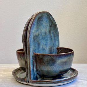 Könnte beinhalten: Ein handgefertigtes Keramik-Servierset mit einzigartigem Design. Das Set enthält ein großes, vertikales Stück mit zwei Schalen und zwei kleinen Tellern. Die Teile sind in Blau- und Brauntönen glasiert und haben eine glänzende Oberfläche.