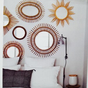 Puede incluir: Una colecci&oacute;n de espejos decorativos con dise&ntilde;os de rayos de sol y circulares. Los espejos est&aacute;n enmarcados con materiales tejidos en tonos naturales y est&aacute;n montados en una pared blanca. La disposici&oacute;n incluye varios tama&ntilde;os y formas, creando una elegante decoraci&oacute;n de pared.