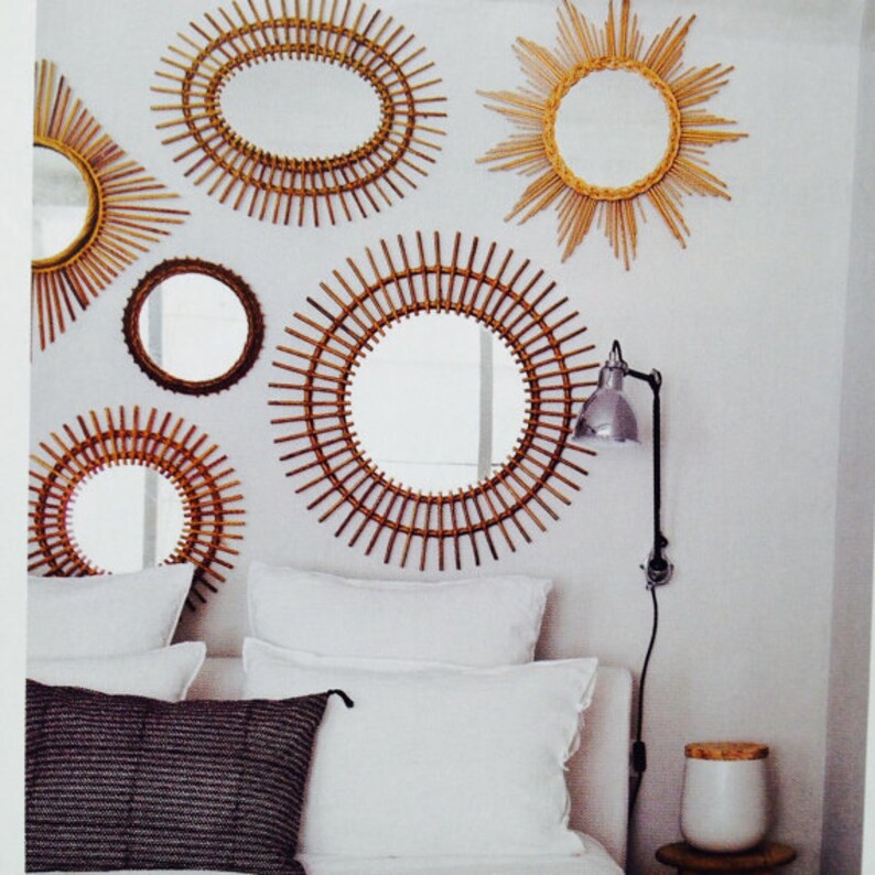 Puede incluir: Una colecci&oacute;n de espejos decorativos con dise&ntilde;os de rayos de sol y circulares. Los espejos est&aacute;n enmarcados con materiales tejidos en tonos naturales y est&aacute;n montados en una pared blanca. La disposici&oacute;n incluye varios tama&ntilde;os y formas, creando una elegante decoraci&oacute;n de pared.