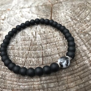 May include: A black beaded bracelet with a white and gray stone accent.